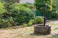 Old well with water pump in a garden. 