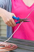 Close up detail of person cutting lengths of copper wire with pliers. 
