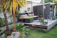 A covered decked seating area with furniture made from reused pallets.