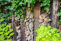 Garden featuring a boundary made using railway sleepers infilled with small logs, branches and twigs. Dipley Mill, Hartley Wintney, Hants, UK. 