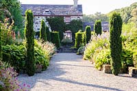 Double herbaceous borders with a frame of English yew buttresses and upright Taxus baccata 'Fastigiata Robusta'. Plas Cadnant Hidden Gardens, Menai Bridge, Anglesey, UK
