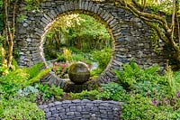 Moon Window in stone wall with cast concrete water feature with shade planting. Fanore, Ireland