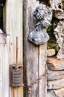 Decorative bust hangs on wooden gate with old fashioned lock. 