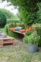 Living gabion bench - Metal gabions lined with turf, planted with lettuce plants, with cushions and pallet table