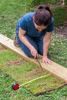Woman using a kitchen knife and wooden guide to trim turf to correct size