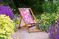 Deck chair with plants perfect for pollination - Anthemis tinctoria 'E.C. Buxton' Dyer's Chamomile AGM and Salvia nemorosa 'Amethyst' Balkan Clary, Erigeron karvinskianus 