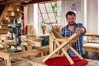 Chris Punch, garden furniture designer in his workshop assembling a footstool from component parts
