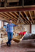 Chris Punch, garden furniture designer, in his workshop, with the range of chairs he produces. 