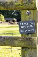 Sign requesting visitors not to feed the donkeys on the fence of their paddock. 