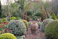 A large oil jar marks the centre of the Rickyard, framed by rusty metal arch and pots of Tulip 'Abu Hassan'. 