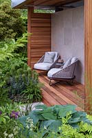 Armchairs on decking by pavilion - The Morgan Stanley Garden for the NSPCC - Sponsor: Morgan Stanley - RHS Chelsea Flower Show 2018