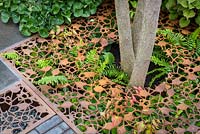 Leaf-shaped permeable paving made of laser cut metal grids over planting of ferns. Urban Flow garden, Sponsor: Thames Water, RHS Chelsea Flower Show, 2018.
