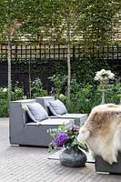 Grey outdoor chair arrangement with yellow cushions, skin, tables, drinks and floral arrangements