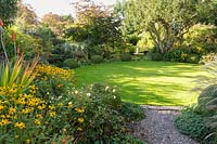 Circular lawn with mixed green foliage planting in beds