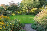 Circular lawn with beds of herbaceous perennials and grasses - Shropshire, UK
