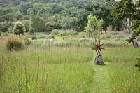 Metal sculpture of Acrobats 'Head over Heels' leads the eye down a grassy path at Dyffryn Fernant