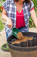 Woman adding aquatic compost to the raised area to create a boggy area within the pond