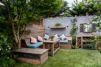 Small courtyard garden in West London with artificial lawn, built in Reclaimed 
Scaffold board seating and dining area with brick barbecue  
Garden designed by James Walsh.