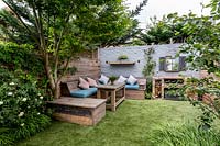 Courtyard garden in West London with artificial lawn and reclaimed scaffold board seating 