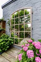 Garden mirror with pink Hydrangea and wood decking