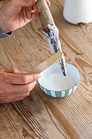 Applying bicarbonate of soda paste to hand dipper using wooden spatula