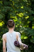 A person holding a yoga mat in the garden