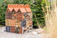 Insect hotel created in wire gabion with a variety of building materials and dried plant material