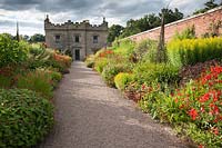 View down hot-coloured borders to castle. Floors Castle, Kelso, Roxburghshire, Scotland, UK.
