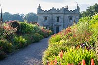 View past hot-coloured borders to castle. Floors Castle, Kelso, Roxburghshire, Scotland, UK.
