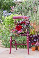 Finished floral arrangement on dark red vintage chair. 