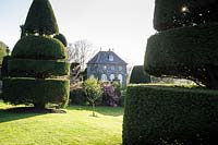 Clipped yews frame a view towards the Orangery at Plas Brondanw, Penrhyndeudraeth, Gwynedd, Wales