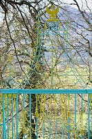 Decorative metalwork around the garden is painted in bright yellow and turquoise. Plas Brondanw, Penrhyndeudraeth, Gwynedd, Wales