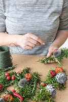 Binding stems of hips, chillies and silver teasels with floristry wire