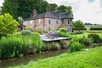 View accross the river to the house and garden, Norfolk, UK.