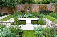 View of formal pond with rill, surrounded by mixed beds with Armillary Sundial in walled city garden. Garden design by Peter Reader Landscapes.