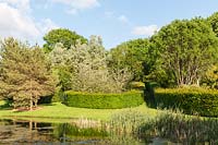 View over lake to clipped Hornbeam hedge enclosures.