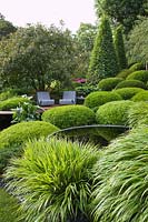 Pool and seating with Buxus, Carpinus betula - Hornbeam and Hakonechloa. Irish Sky Garden, RHS Chelsea Flower Show.