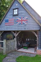 Tool shed displaying various tools featuting The USA flag and the Union Jack above. Brookside