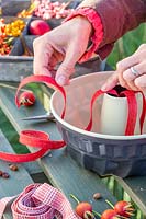 Woman adding lengths of ribbon to bundt cake tin prior to adding bird feed mix, to help remove cake from tin if it gets stuck.