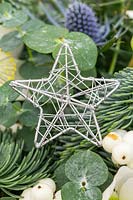 Decorative silver star pick in christmas floral arrangement.