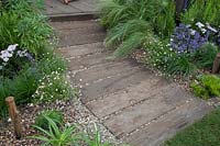 Railway sleeper path and coastal planting in Southend Council 'By The Sea' garden at RHS Hampton Court Flower Show, London, 2017.
