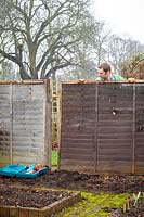 Man repairing wooden fence panels.