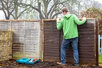 Man repairing wooden fence panels. 