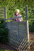 Woman inspecting a storm damaged fence panel. 