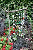 Home made decorative structure with glass jar lids in a flowerbed