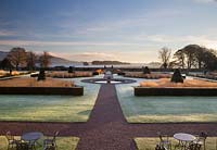 Perfect symmetry is provided by the view down central border and over the clipped yew, ornamental grasses and pond to Loch Leven