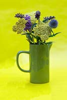 Green jug of summer flowers including Achillea 'Moonshine' - Yarrow,  Buddleia davidii 'Nanho Blue' - Butterfly Bush and Echinops ritro - Globe Thistle. 