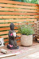 Decorated with Buddha holding a candle, sage to smudge and incense sticks on wooden balcony. 