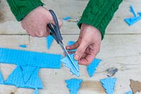 Cutting one foam Christmas tree shape into two halves for edge of hand stamp