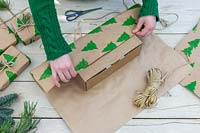 Woman wrapping gift with hand stamped christmas wrapping paper.